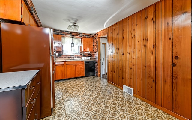 kitchen with dishwasher, decorative backsplash, wooden walls, stainless steel fridge, and sink