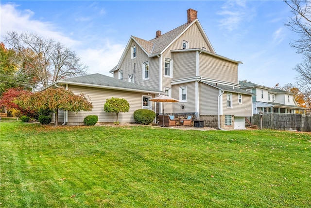 rear view of house with a patio and a lawn