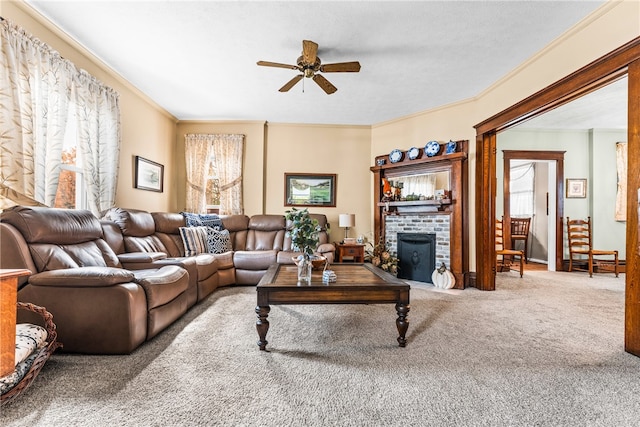 carpeted living room featuring a brick fireplace, ornamental molding, and ceiling fan