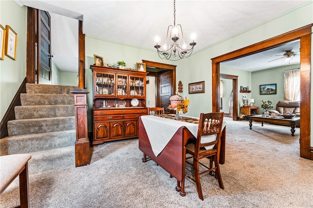 carpeted dining area with ceiling fan with notable chandelier