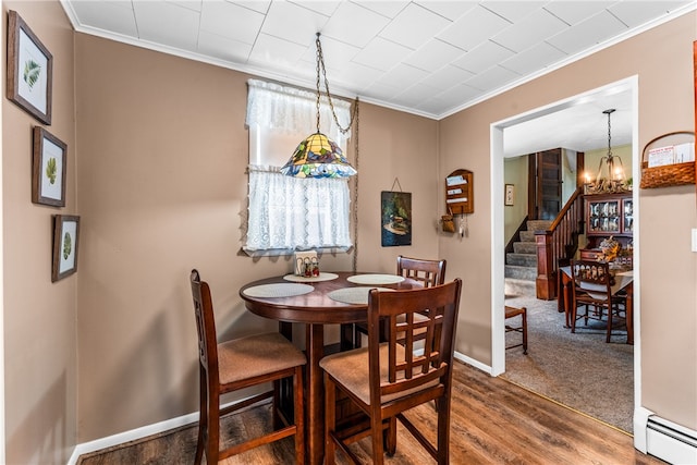 dining area with ornamental molding, a chandelier, a baseboard heating unit, and hardwood / wood-style flooring