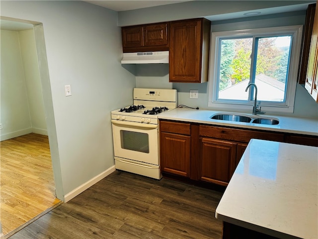 kitchen featuring sink, white gas range oven, dark wood-type flooring, and extractor fan