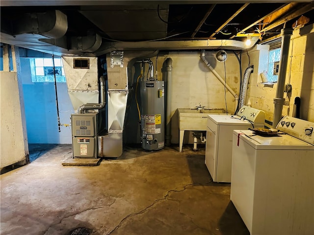 basement featuring sink, washing machine and dryer, heating unit, and water heater