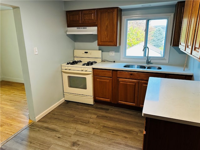 kitchen with extractor fan, white gas stove, sink, and dark wood-type flooring