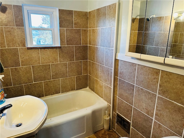 bathroom with vanity, tiled shower / bath combo, and tile walls