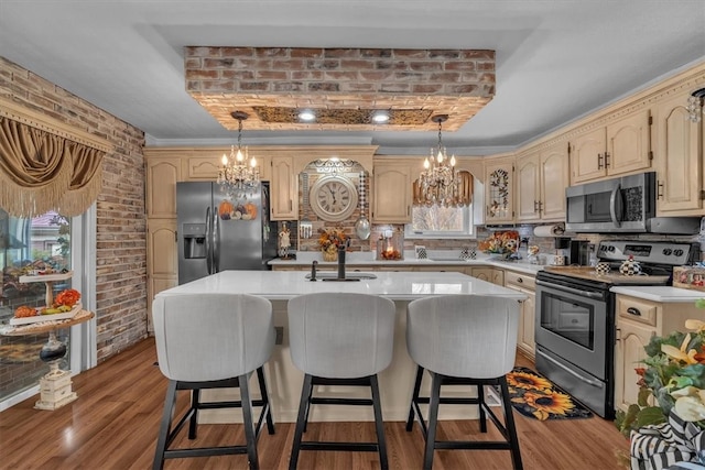 kitchen with light hardwood / wood-style flooring, an island with sink, brick wall, plenty of natural light, and appliances with stainless steel finishes