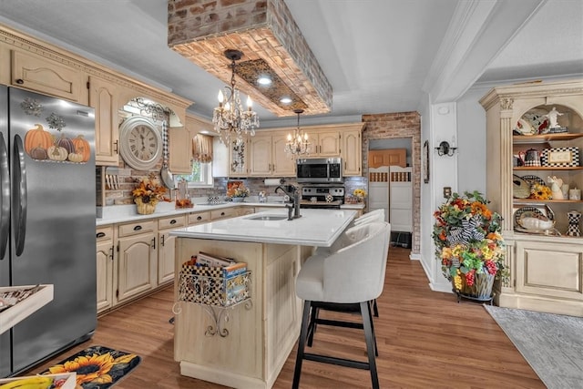 kitchen featuring stainless steel appliances, decorative backsplash, light hardwood / wood-style flooring, and a center island with sink