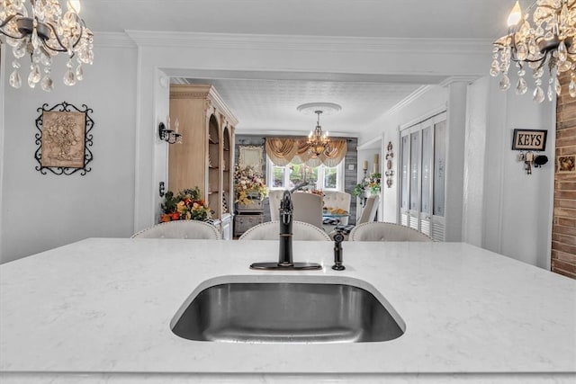 kitchen featuring sink, crown molding, a notable chandelier, and decorative light fixtures