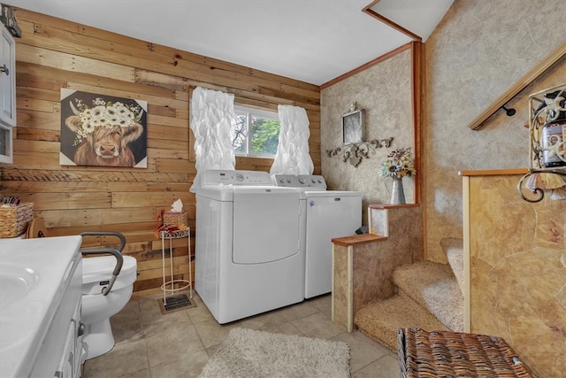 washroom with wood walls, separate washer and dryer, and light tile patterned floors