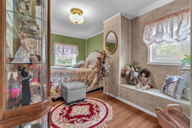 bedroom with ornamental molding, multiple windows, and hardwood / wood-style flooring