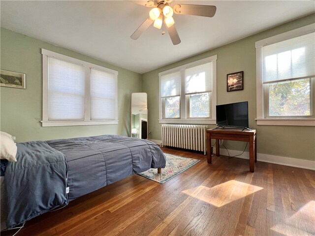 bedroom with ceiling fan, wood-type flooring, and radiator