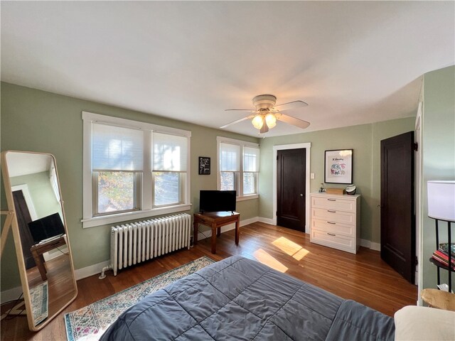 bedroom with dark wood-type flooring, radiator, and ceiling fan