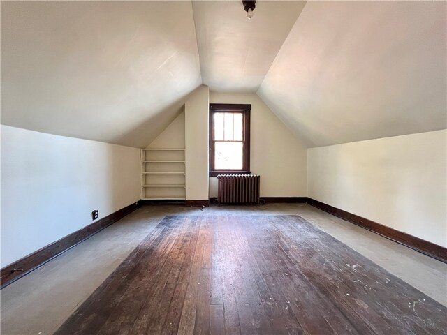 additional living space featuring built in shelves, hardwood / wood-style floors, radiator heating unit, and lofted ceiling