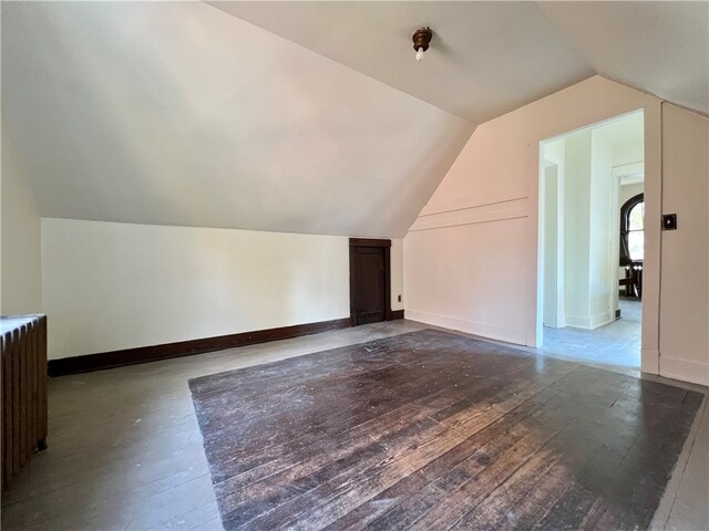 additional living space with hardwood / wood-style floors, radiator, and vaulted ceiling