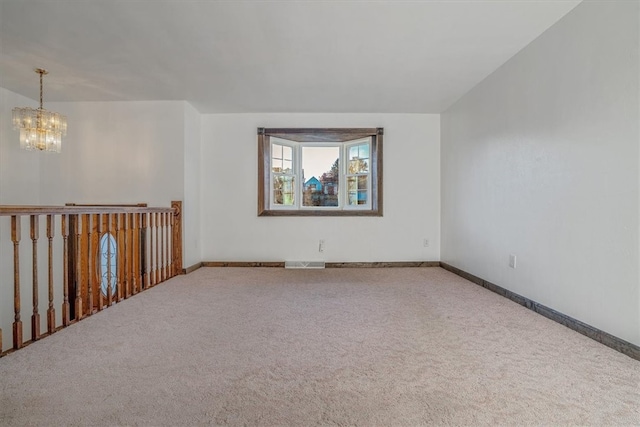 carpeted empty room with an inviting chandelier