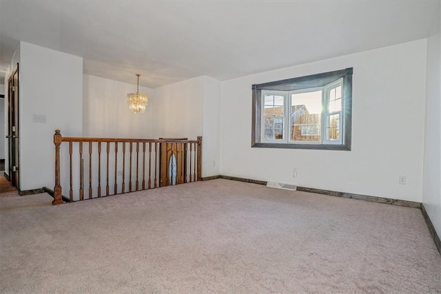 spare room with a notable chandelier and carpet flooring