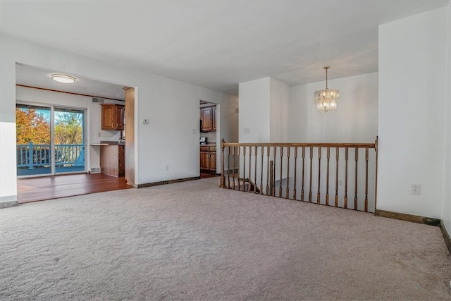 carpeted empty room with a notable chandelier