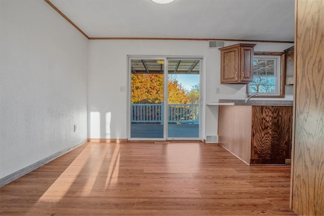 unfurnished dining area featuring crown molding and light hardwood / wood-style floors