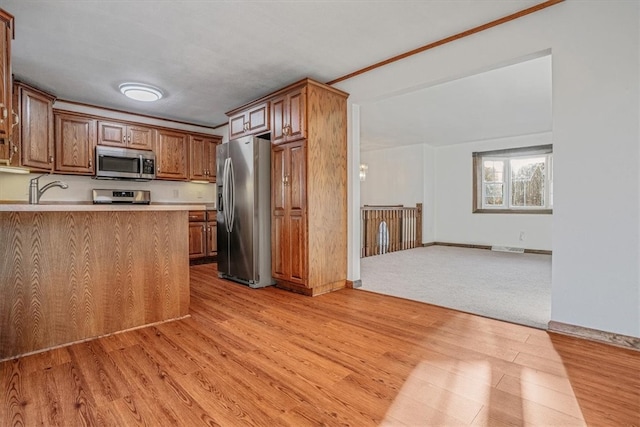 kitchen with light hardwood / wood-style floors, stainless steel appliances, and kitchen peninsula