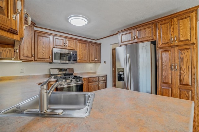 kitchen with crown molding, stainless steel appliances, a textured ceiling, and sink