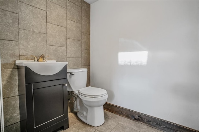 bathroom with toilet, vanity, tile patterned floors, and tile walls