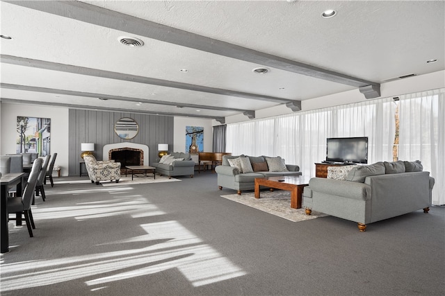 living room featuring carpet flooring, beamed ceiling, and a textured ceiling