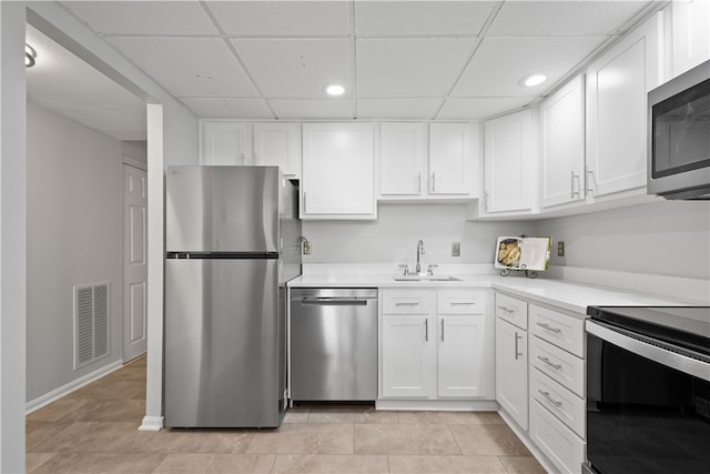 kitchen featuring white cabinets, light tile patterned floors, a paneled ceiling, sink, and stainless steel appliances