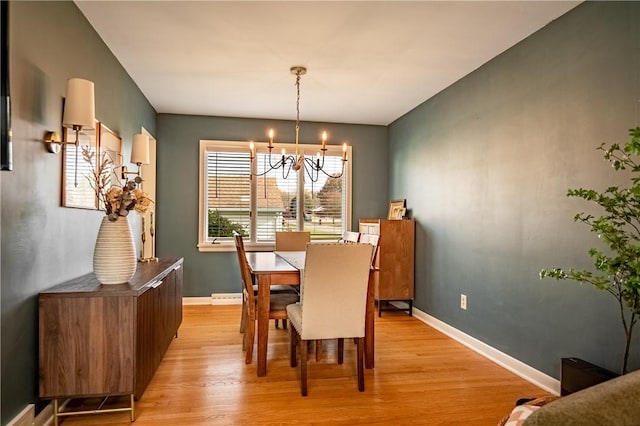 dining area with an inviting chandelier and light hardwood / wood-style flooring