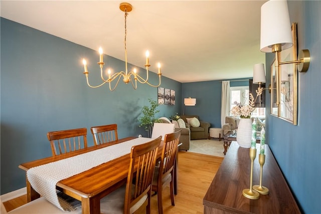 dining space with light wood-type flooring and an inviting chandelier