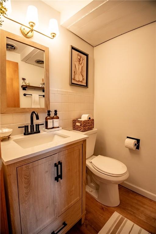 bathroom featuring tasteful backsplash, vanity, wood-type flooring, and toilet