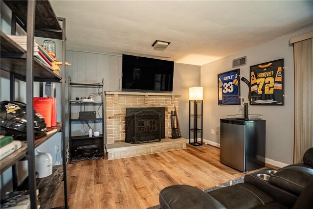 living room featuring a stone fireplace and wood-type flooring