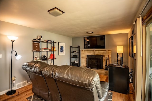 living room featuring a stone fireplace and light wood-type flooring