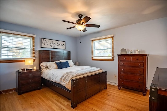 bedroom with baseboard heating, ceiling fan, and light wood-type flooring