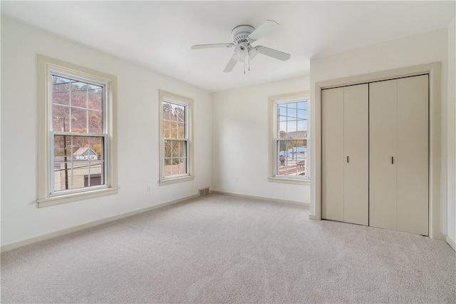 unfurnished bedroom featuring a closet, ceiling fan, and light carpet