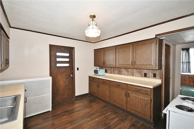 kitchen featuring dark hardwood / wood-style flooring, crown molding, pendant lighting, and electric stove