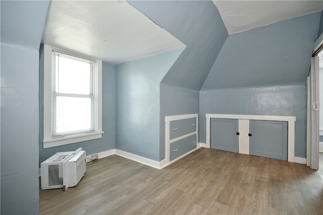 bonus room featuring light hardwood / wood-style floors, a wall mounted air conditioner, and vaulted ceiling