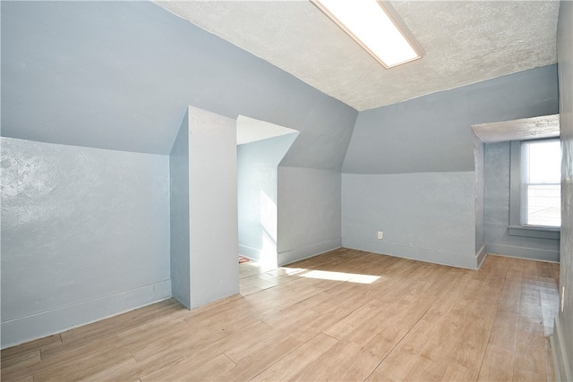 bonus room featuring vaulted ceiling, a textured ceiling, and light hardwood / wood-style floors