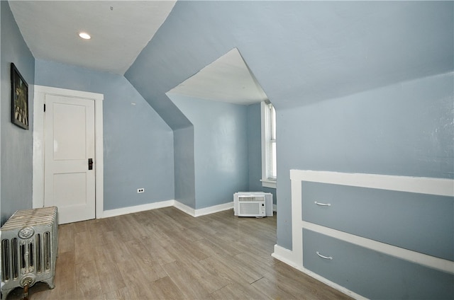 bonus room with a wall mounted air conditioner, vaulted ceiling, and light wood-type flooring