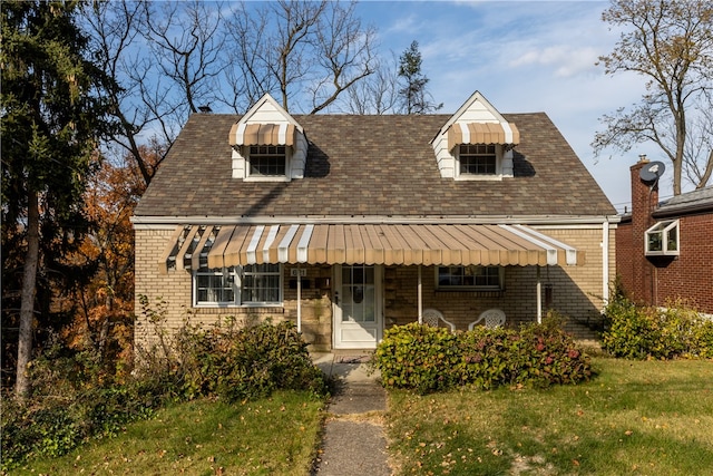 cape cod home featuring a front lawn