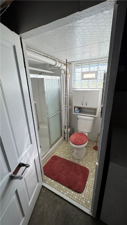 bathroom featuring a shower with shower door and toilet