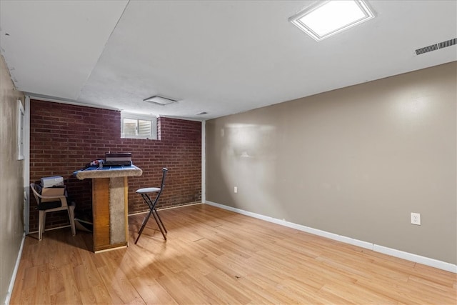 office space featuring brick wall and light hardwood / wood-style floors