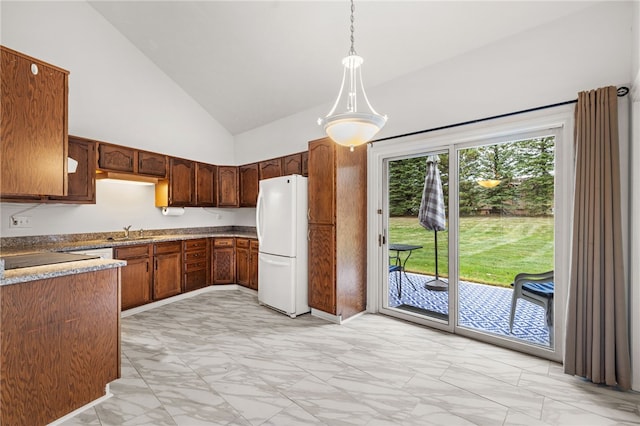 kitchen with white fridge, high vaulted ceiling, hanging light fixtures, and sink