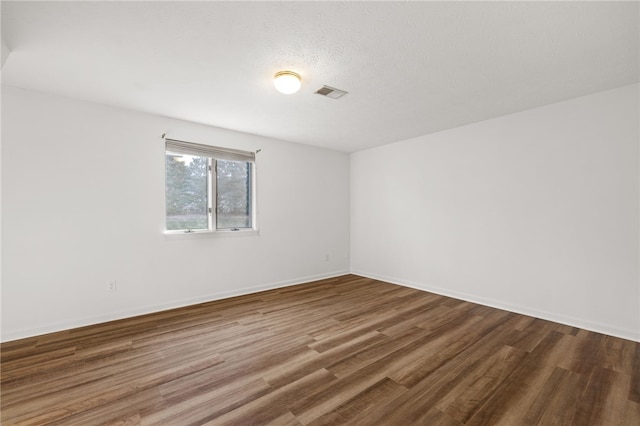 spare room featuring hardwood / wood-style flooring and a textured ceiling