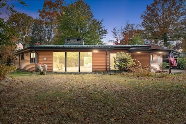 back house at dusk featuring a yard and a patio area