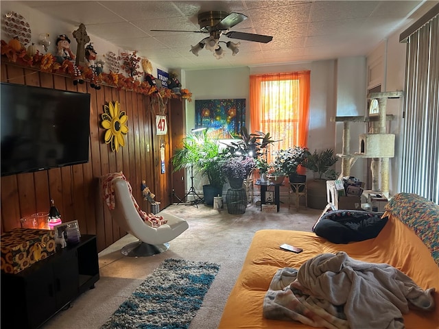 living room with wood walls, light colored carpet, and ceiling fan