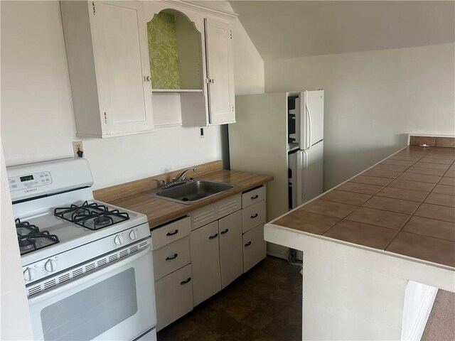 kitchen with sink, white range with gas cooktop, white cabinets, and dark tile patterned flooring