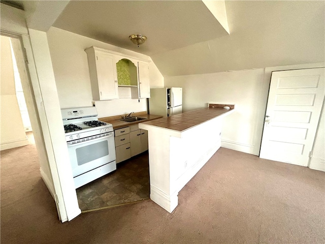 kitchen with white appliances, sink, kitchen peninsula, dark carpet, and tile counters