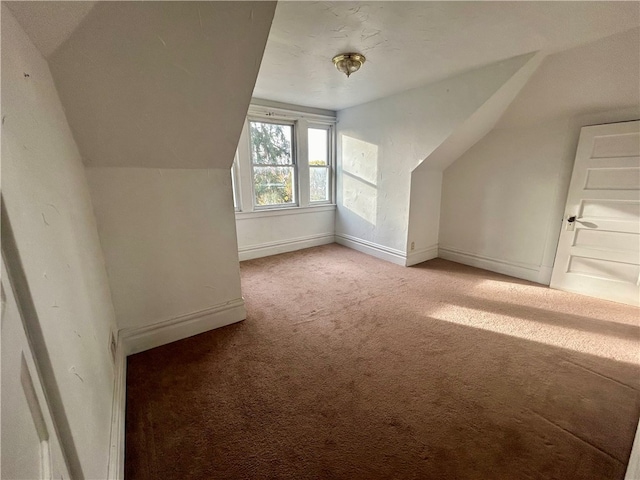 additional living space featuring vaulted ceiling and light carpet