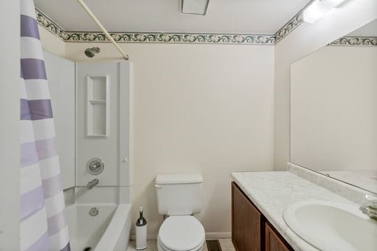 full bathroom featuring vanity, shower / tub combo with curtain, and toilet