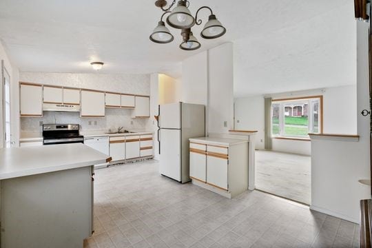 kitchen featuring white cabinetry, sink, pendant lighting, light colored carpet, and white appliances